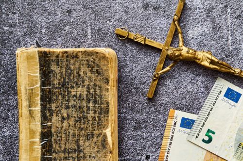 Kreuz, Buch und Geldscheine